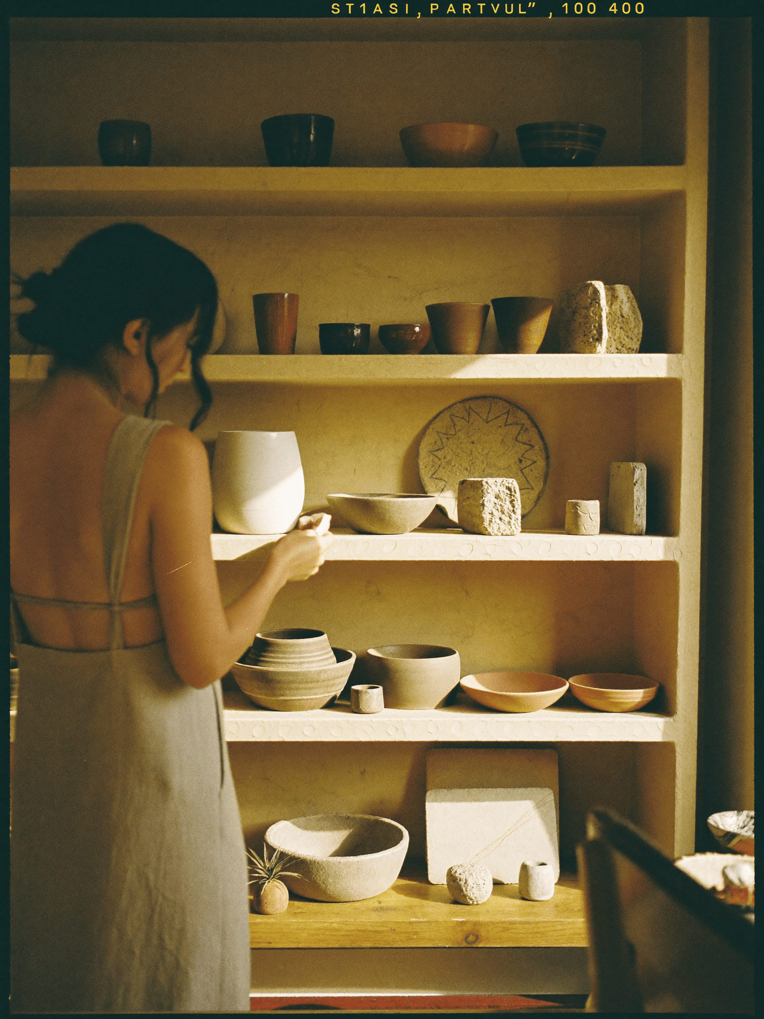 A designer arranging ceramics and stone samples on a plaster shelf.
